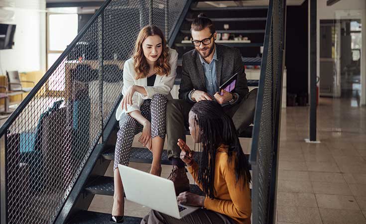 coworkers discussing something while sitting on stairs