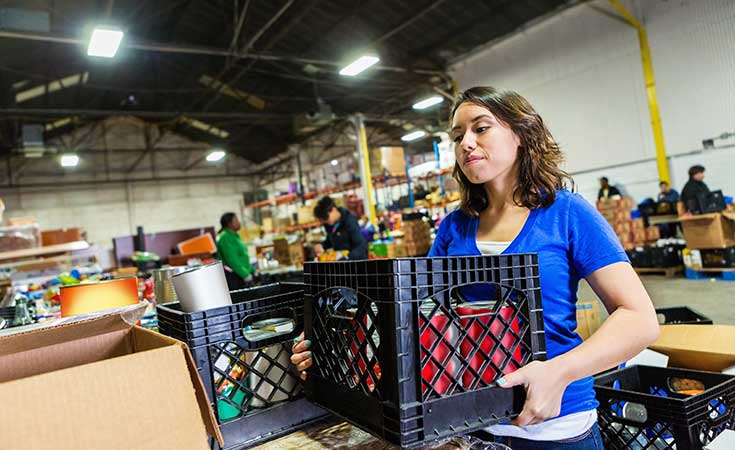 woman stacking crates full of items