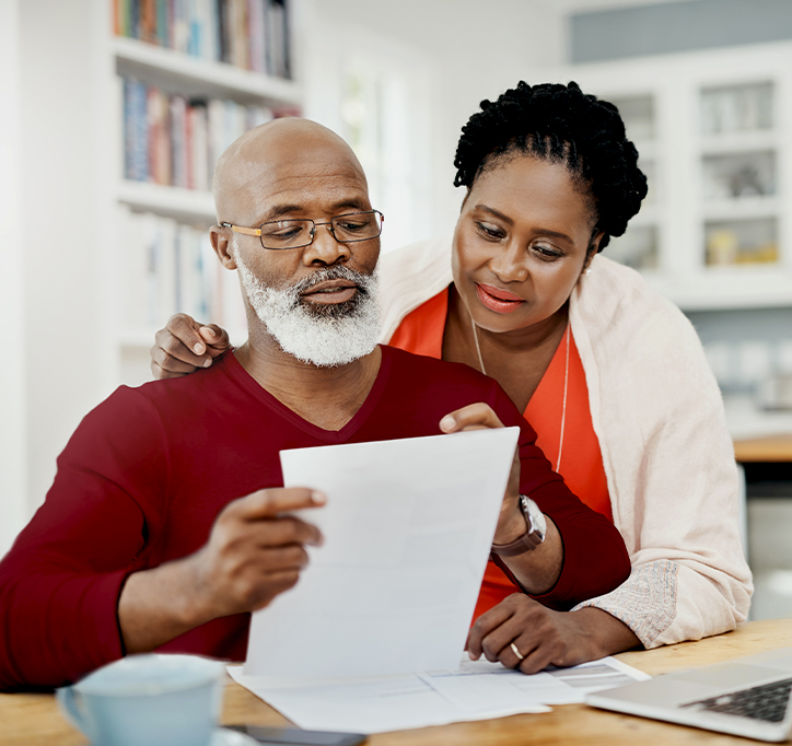 older black couple embracing and looking at a piece of paper together