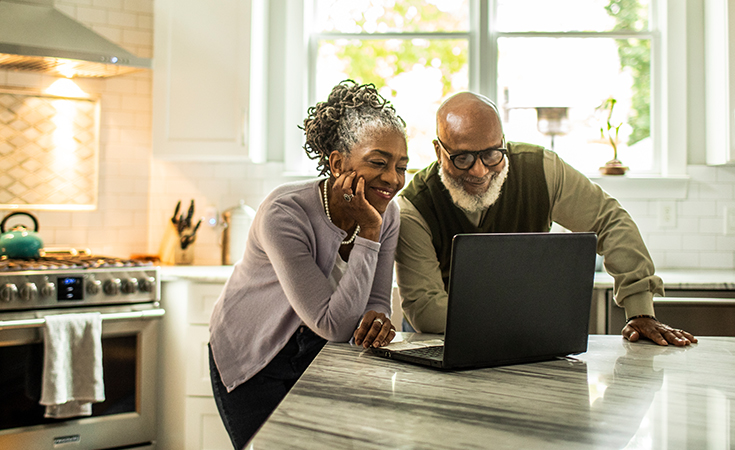 older black couple smiling and looking at a computer
